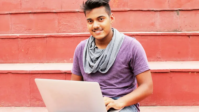 A student with a laptop on red steps